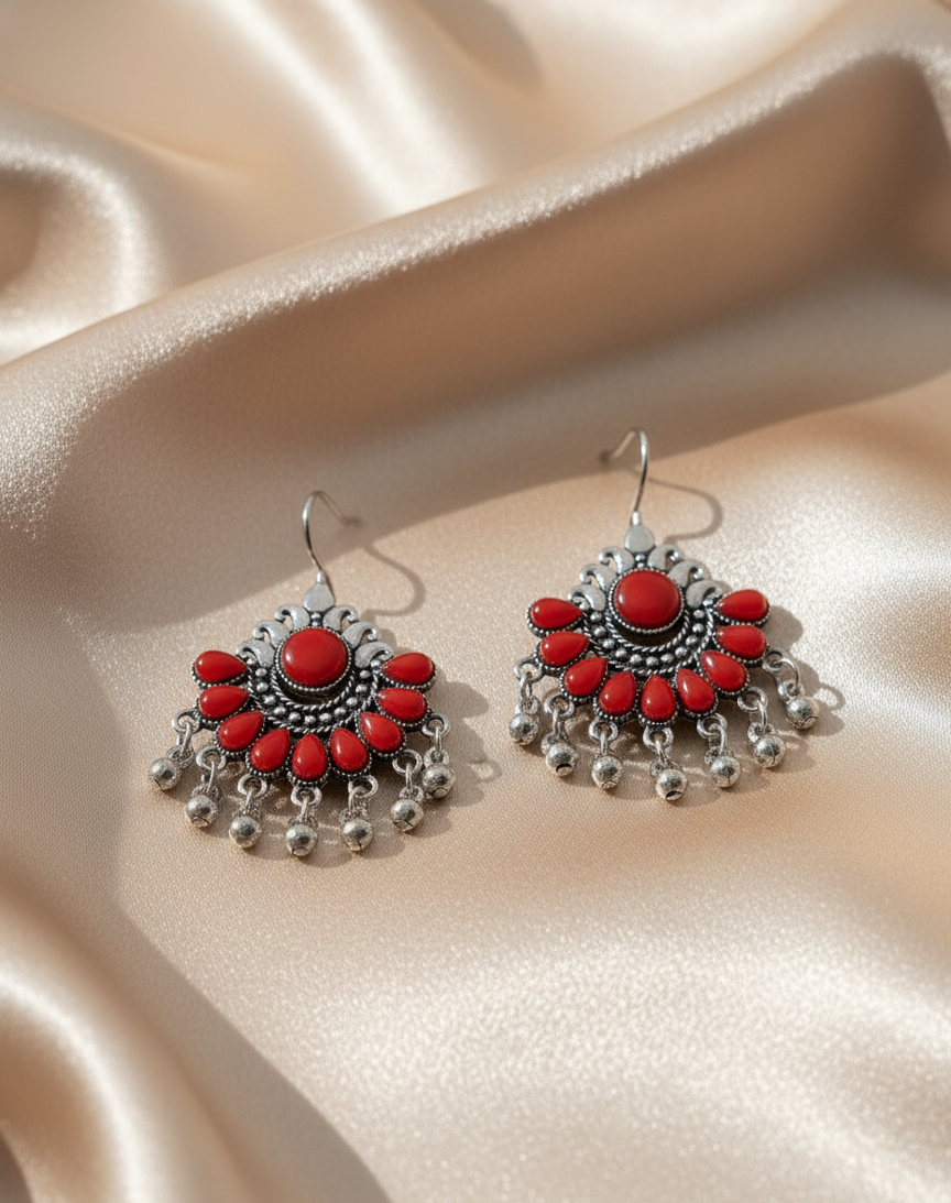 Ornate earrings with red stones on a beige fabric background