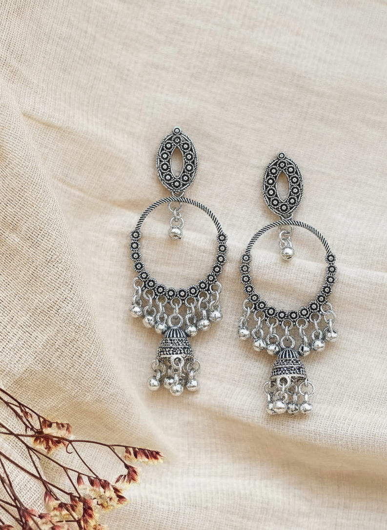 Pair of silver earrings on a beige fabric background
