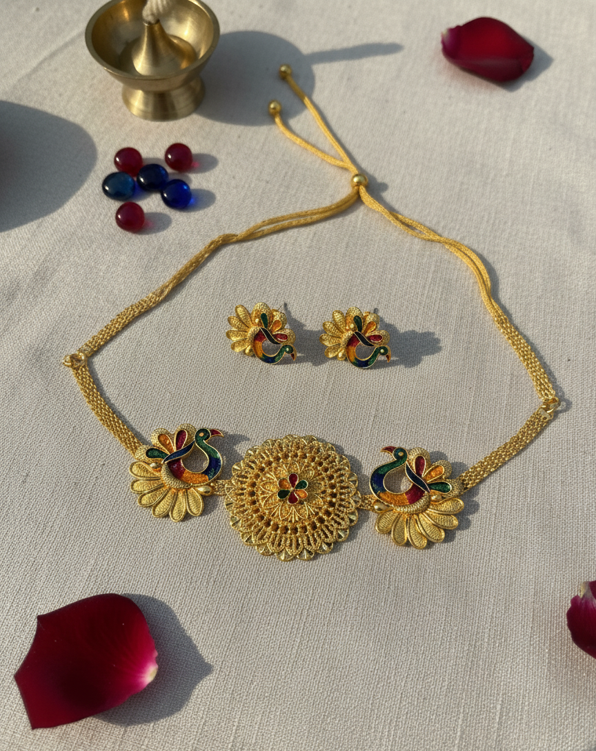 Gold necklace and earrings with colorful stones on a textured surface with red petals.