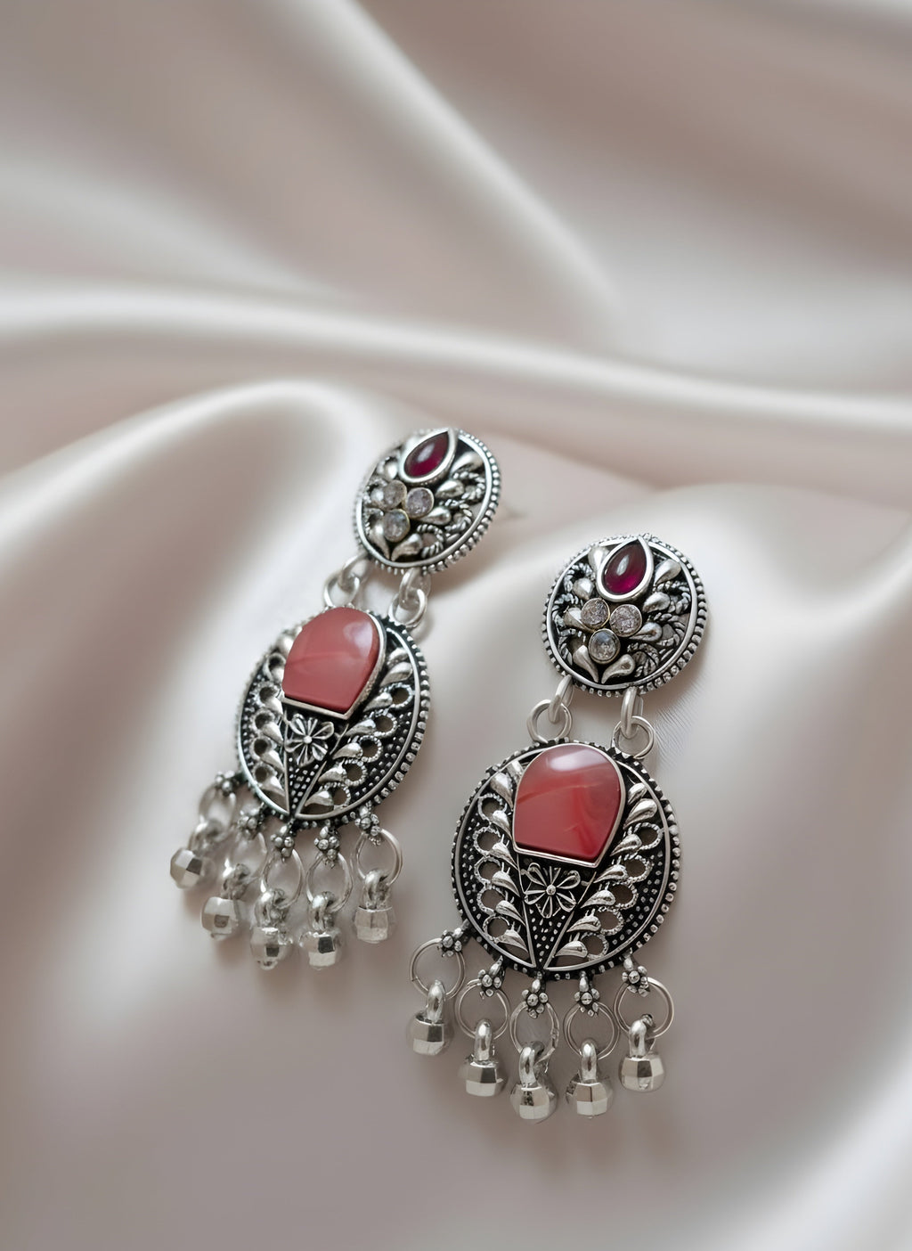 Ornate earrings with pink stones on a soft fabric background