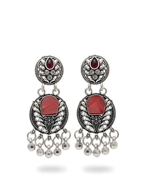 Pair of earrings with red stones and dangling beads on a white background