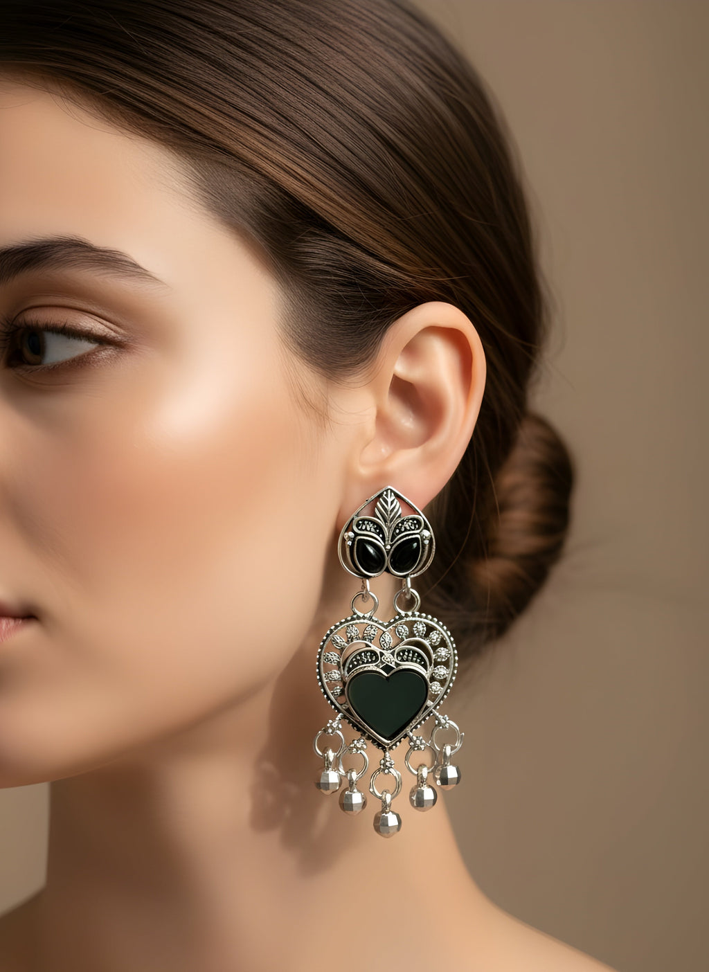 Close-up of a woman wearing a decorative earring with a heart design.