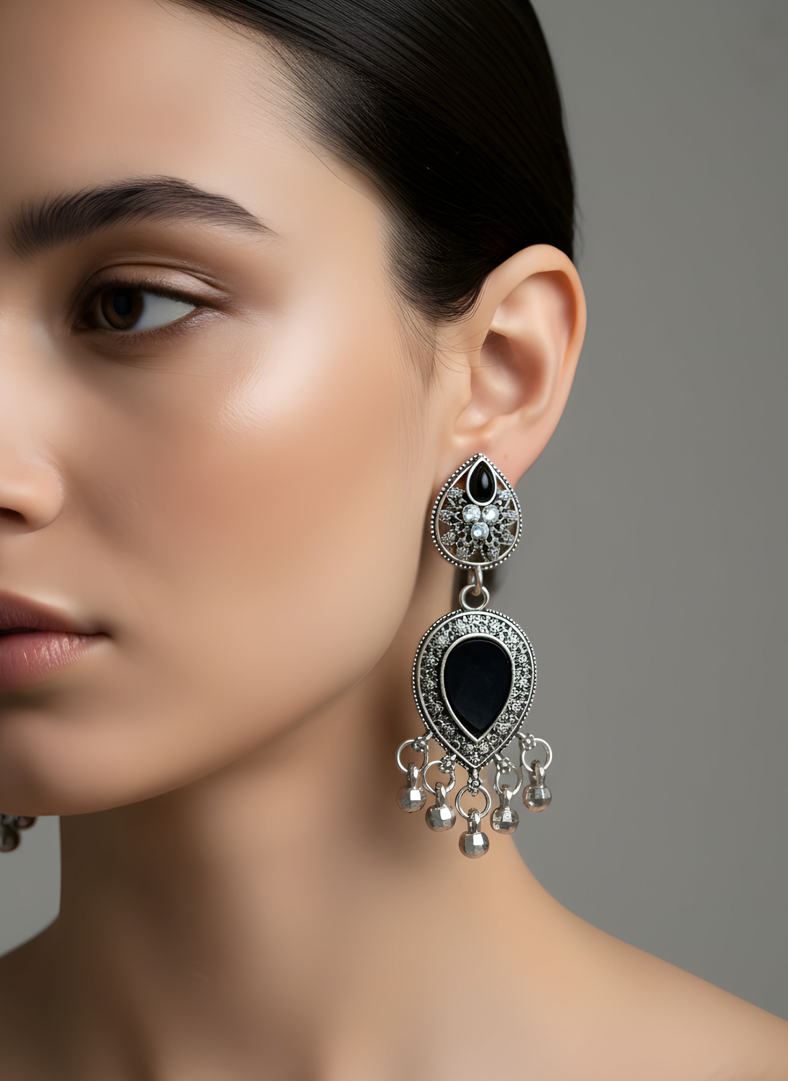 Close-up of a woman wearing an elegant black and silver earring against a neutral background