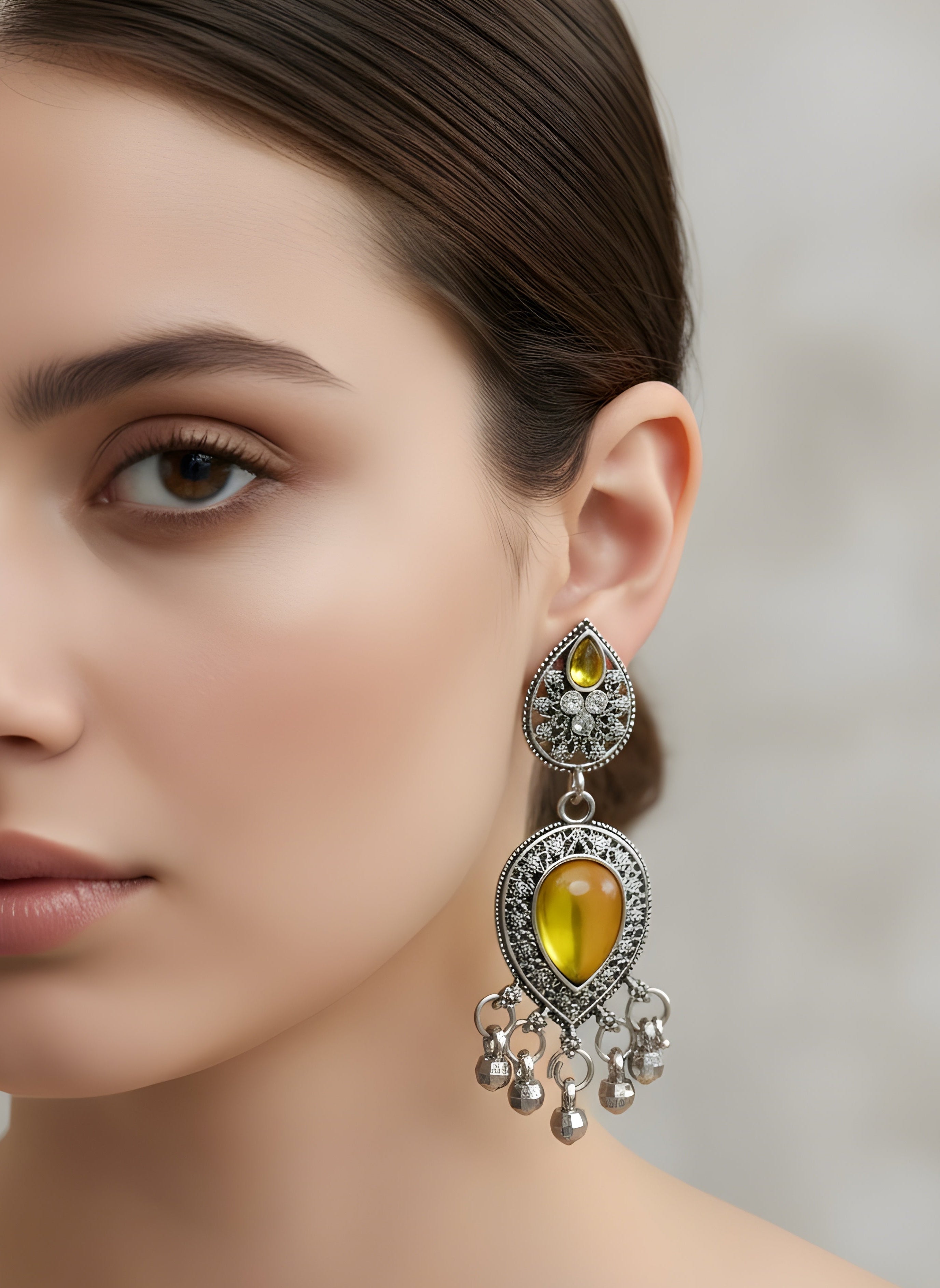 Close-up of a woman wearing a yellow gemstone earring with silver details.
