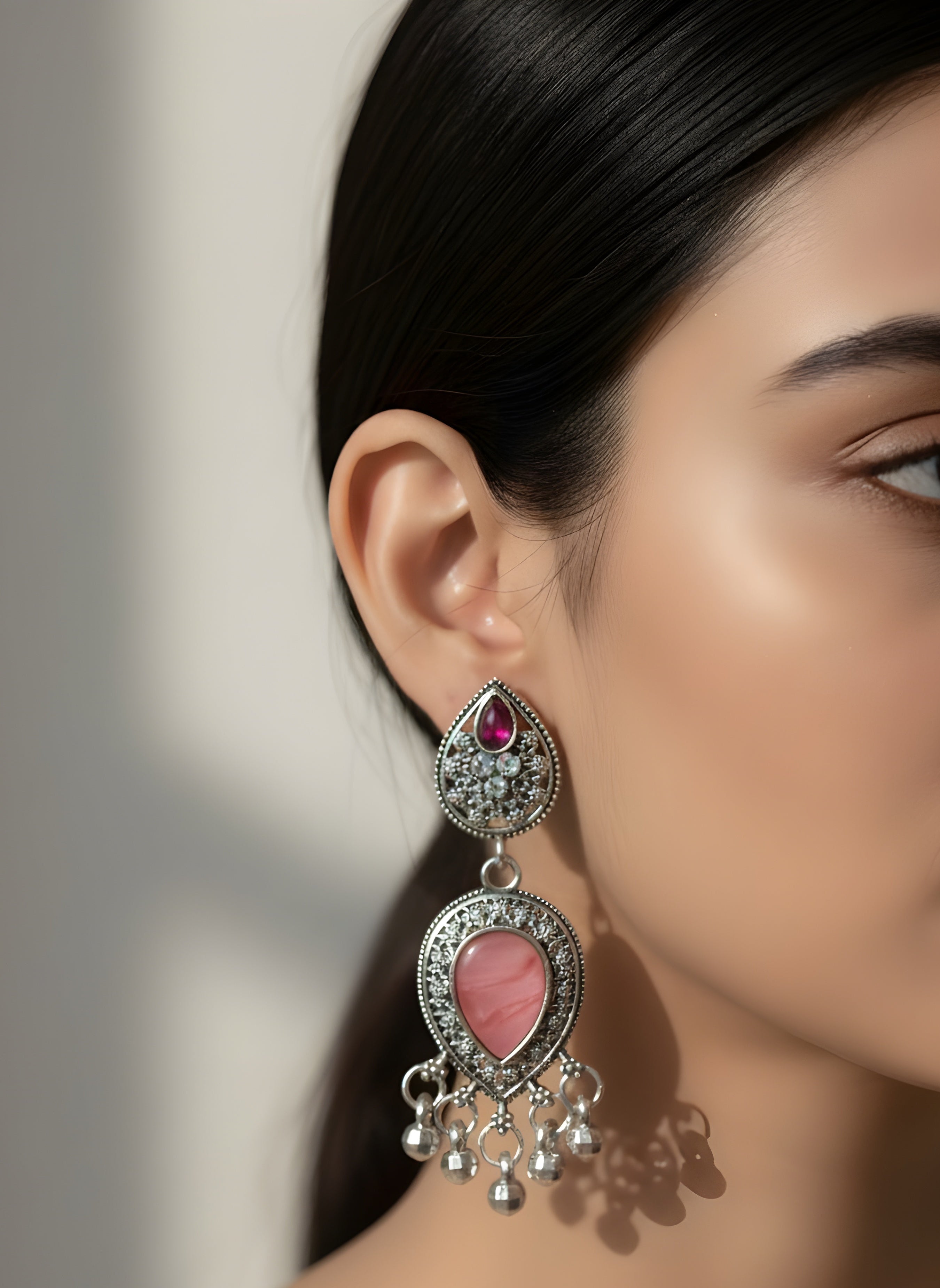 Close-up of a woman wearing a decorative earring with a pink gemstone.