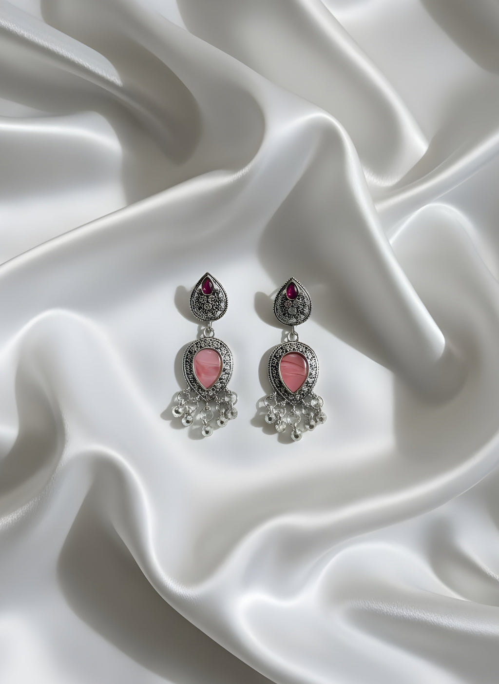 Pair of earrings with pink stones on a white satin background