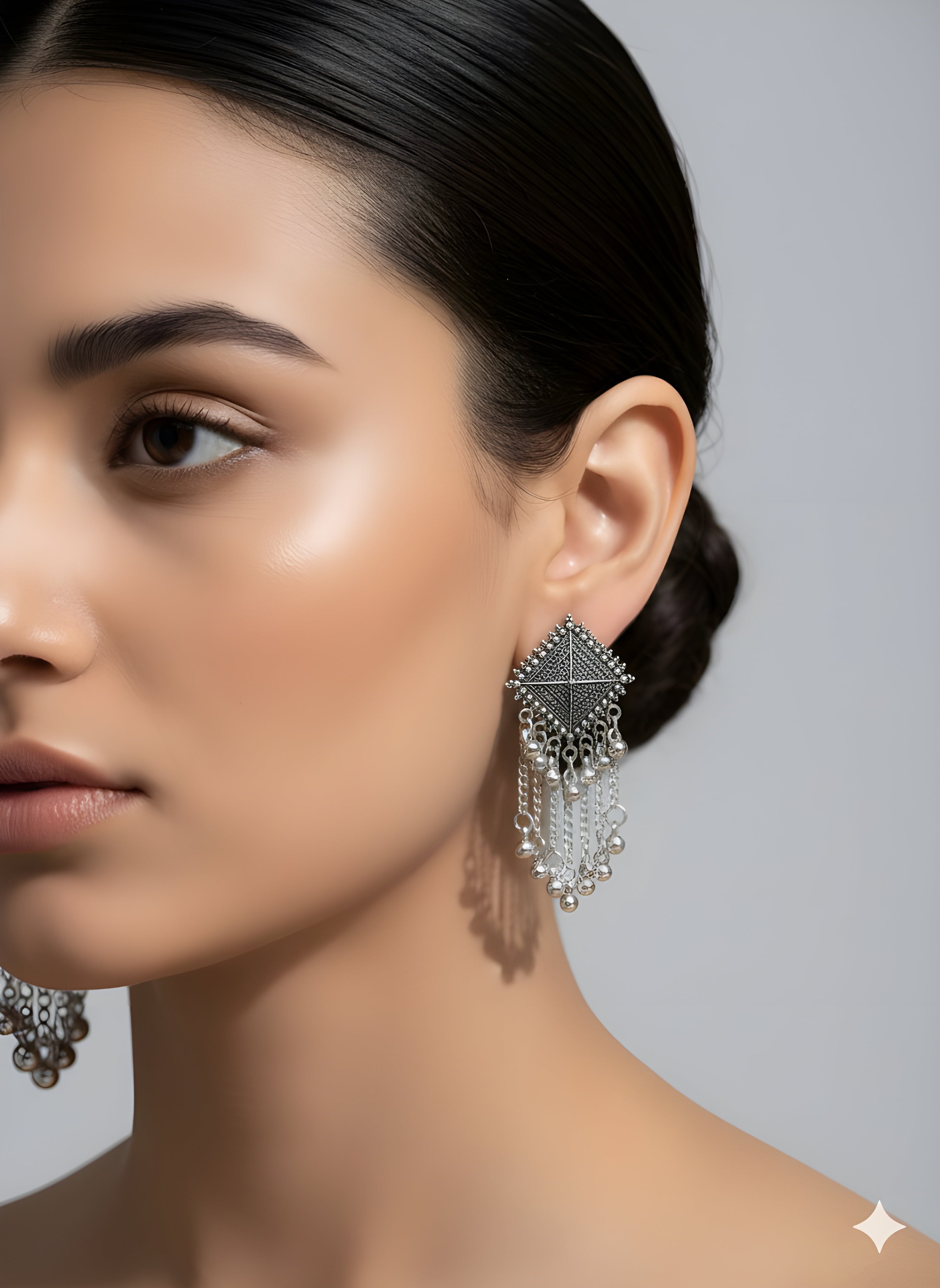 Close-up of a woman wearing silver earrings with a gray background