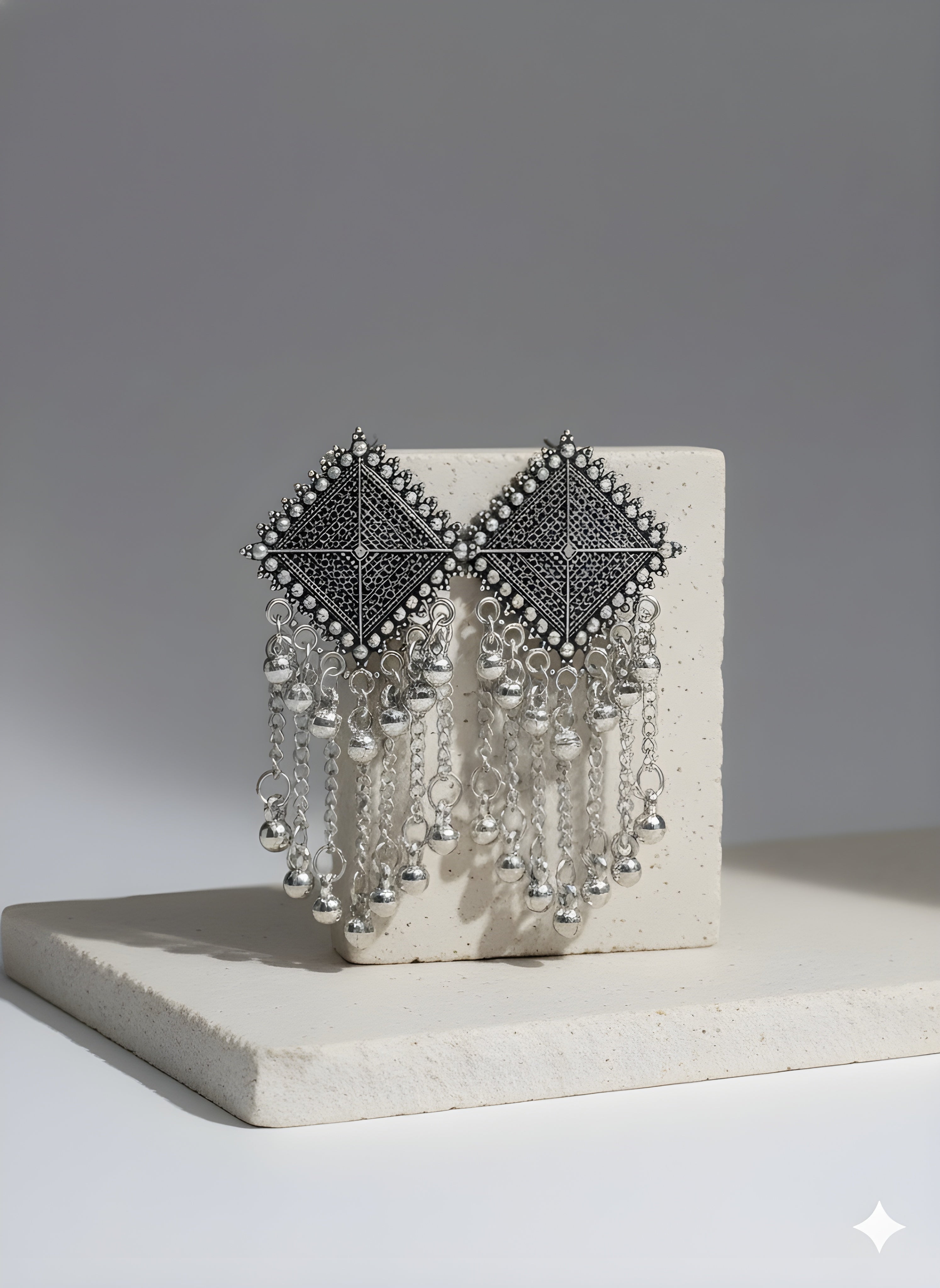 Decorative wall art piece with geometric design and hanging elements on a neutral background