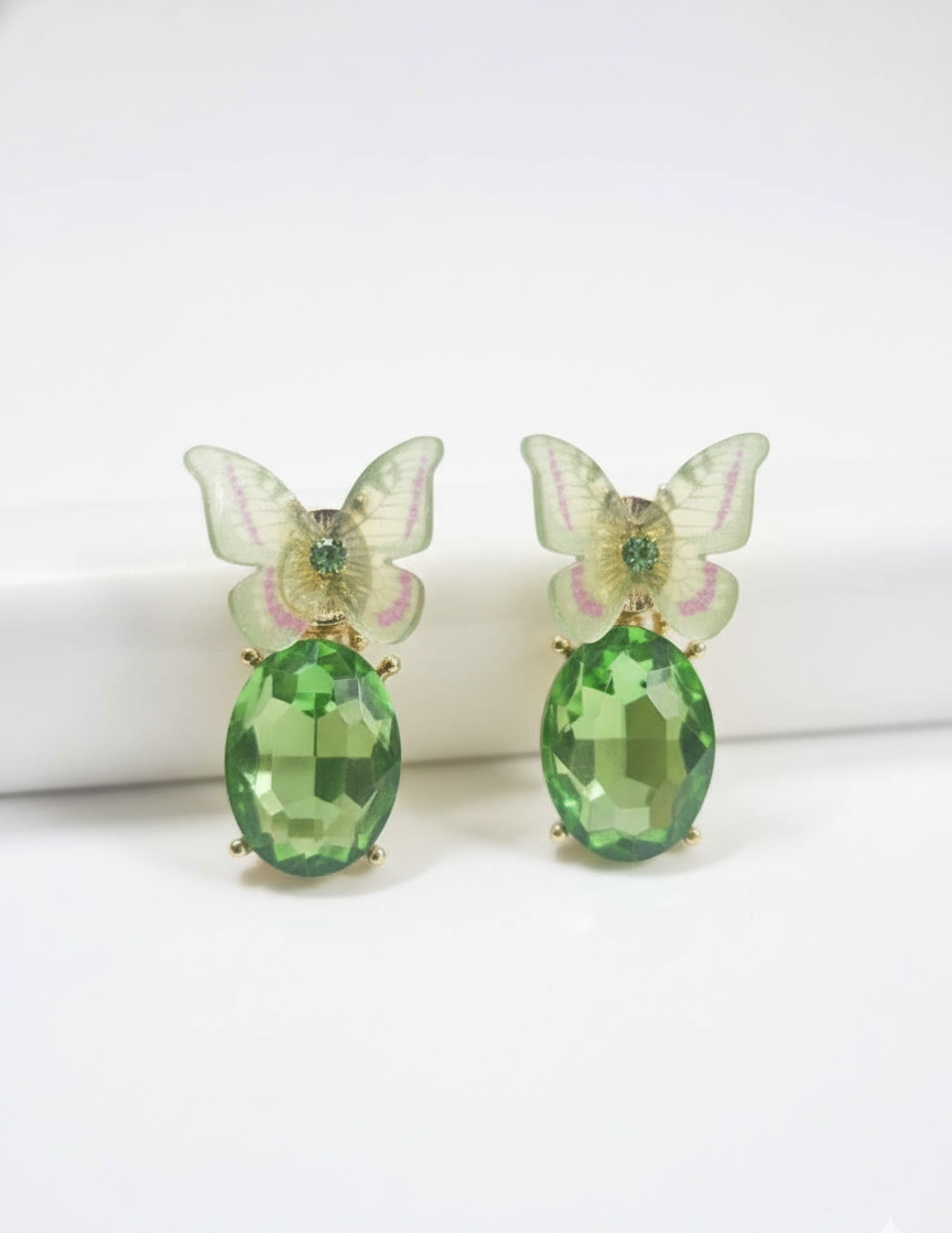 Butterfly-shaped earrings with green gemstones on a white background