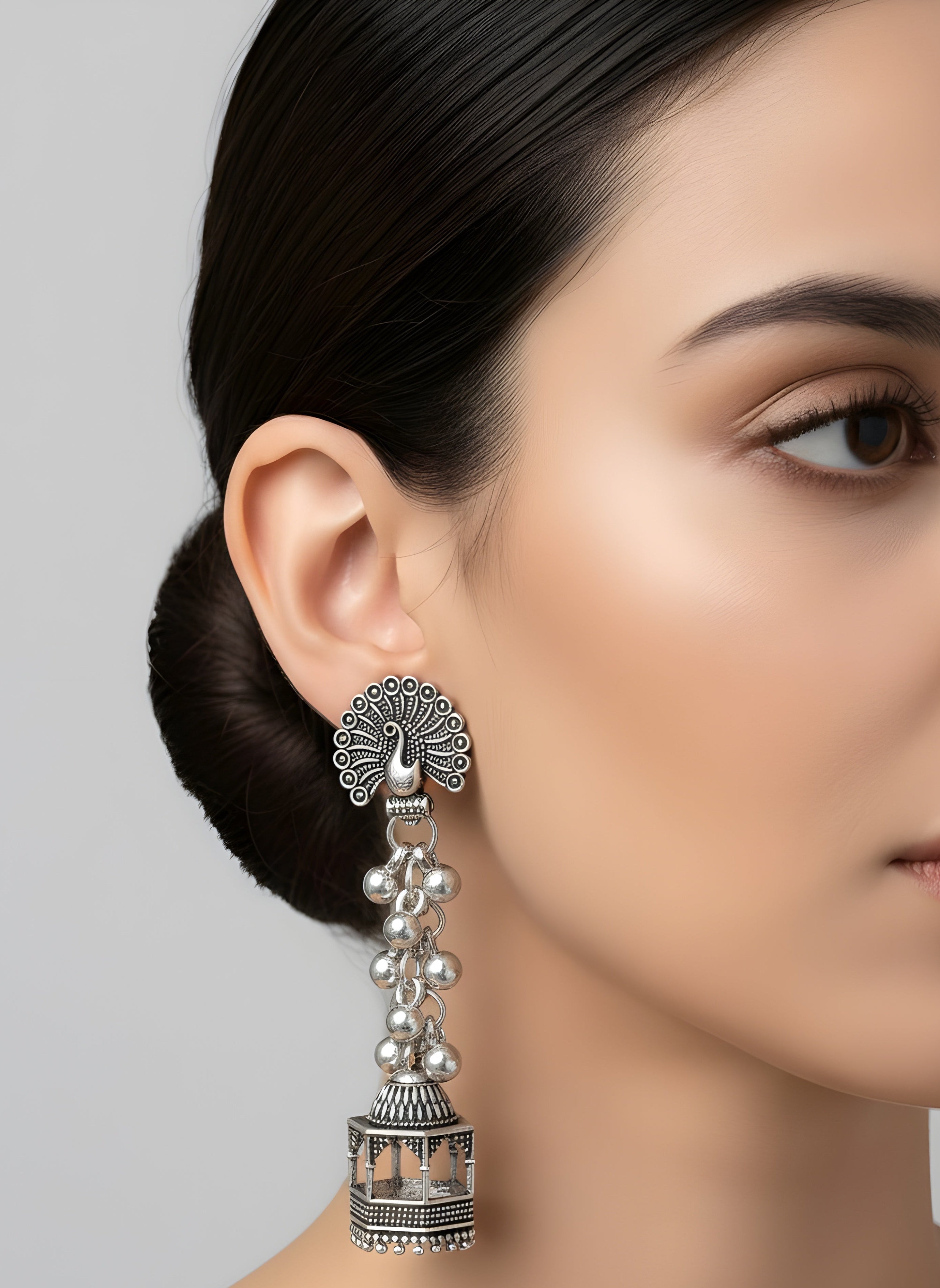 Silver earrings worn by a model against a neutral background