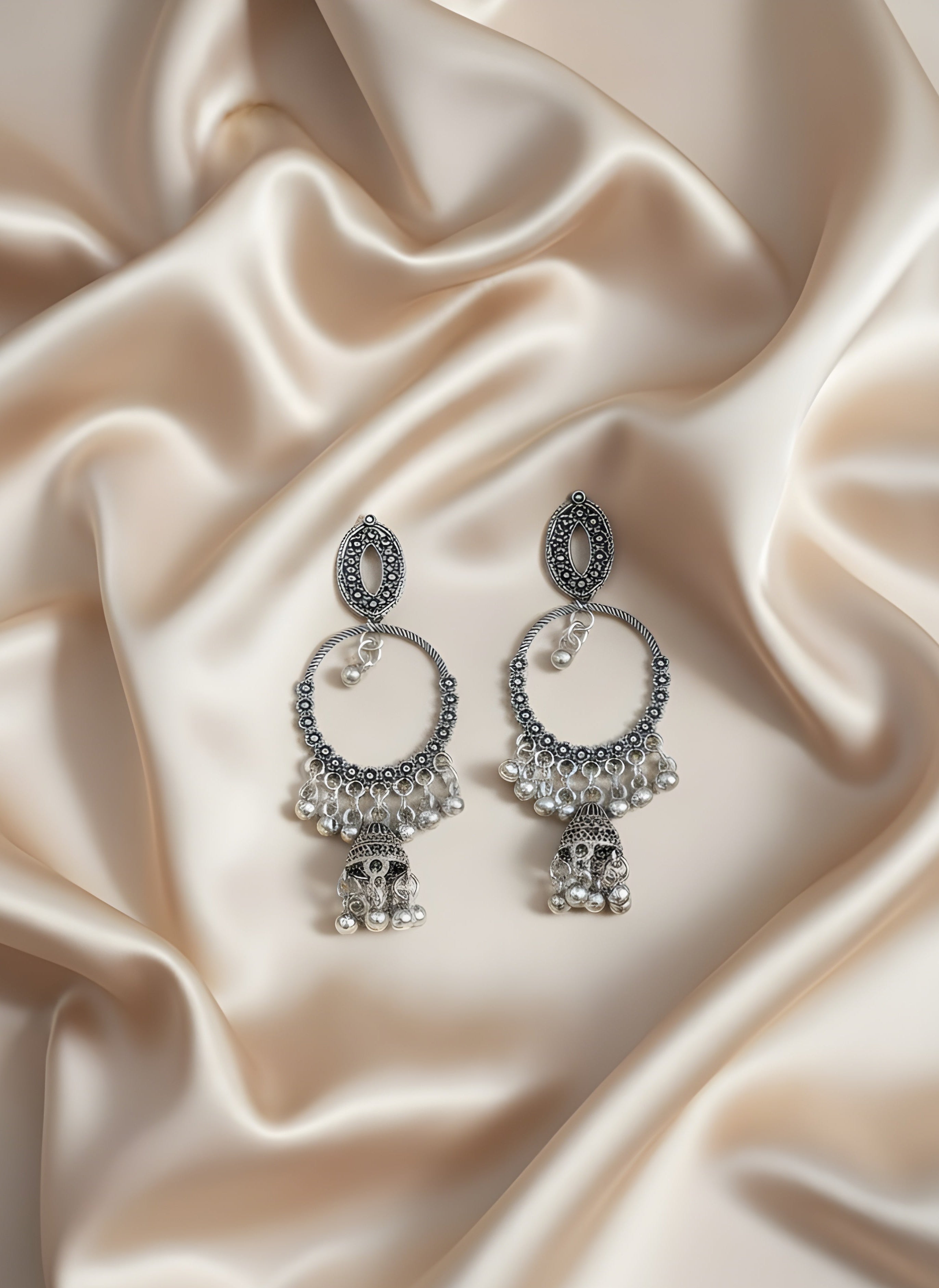 Silver earrings on a beige satin fabric