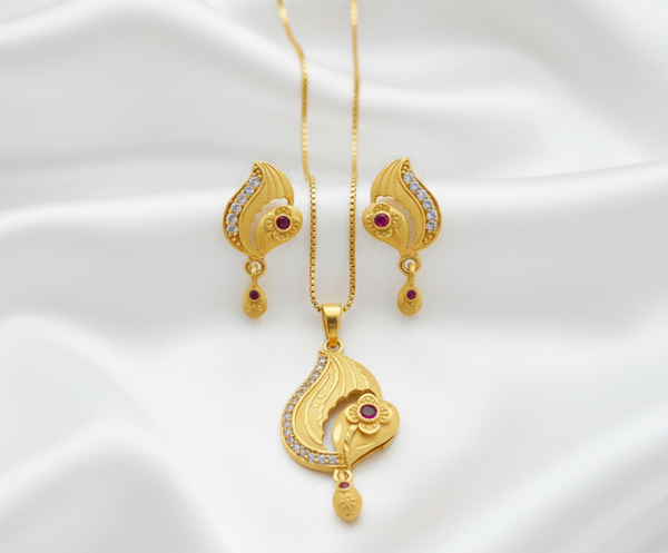 Gold jewelry set with necklace, pendant, and earrings on a white satin background