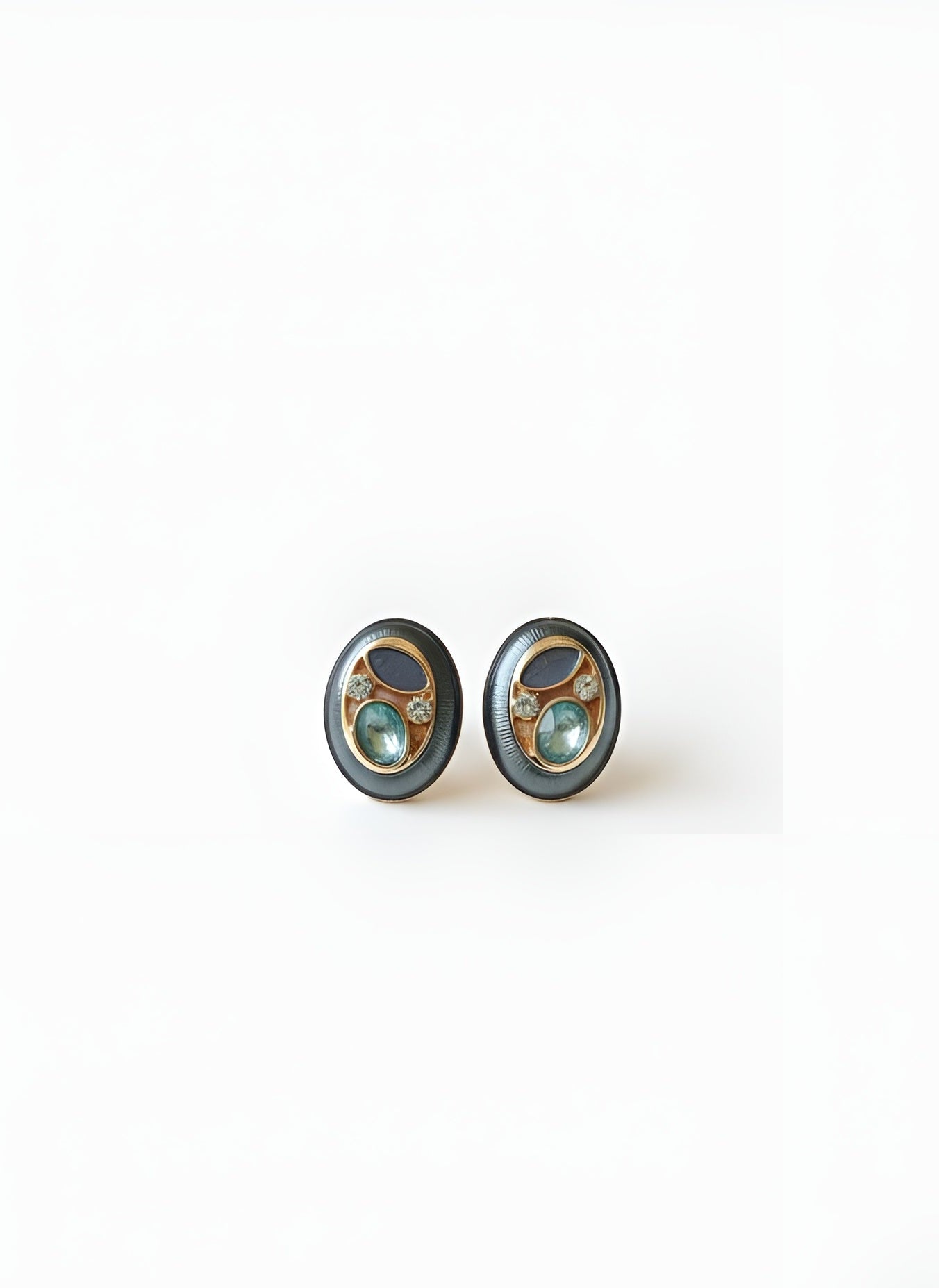 Pair of round earrings with green gemstones on a white background