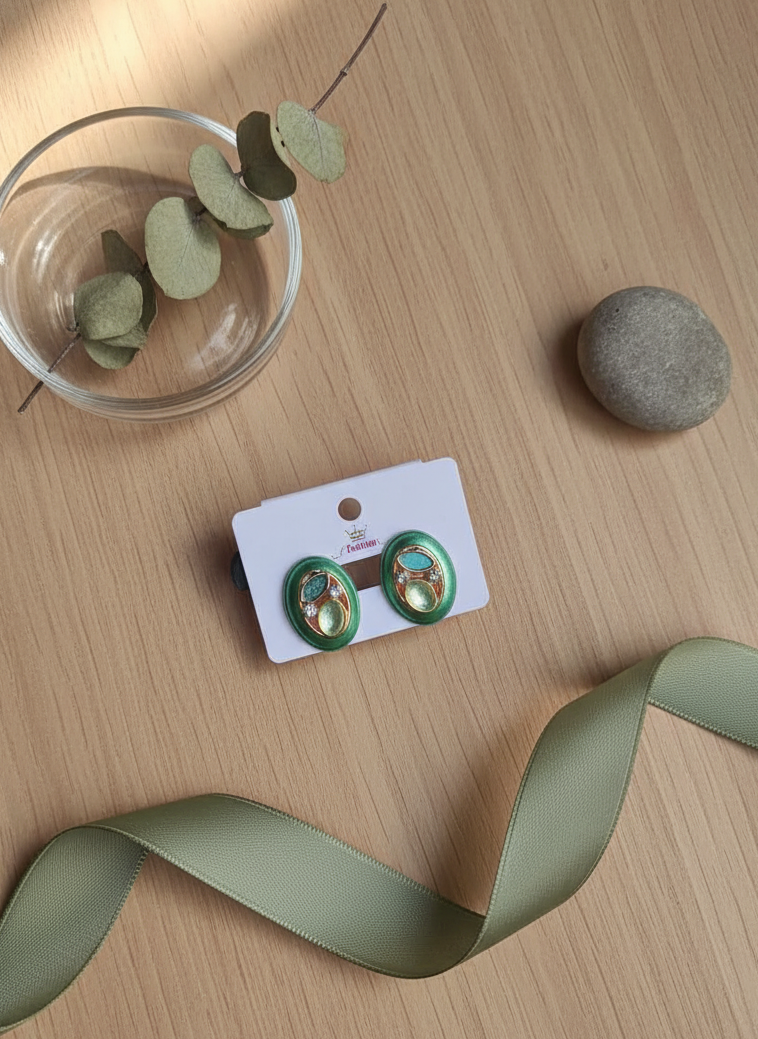 Green earrings on a card with a green ribbon and small plant on a wooden surface