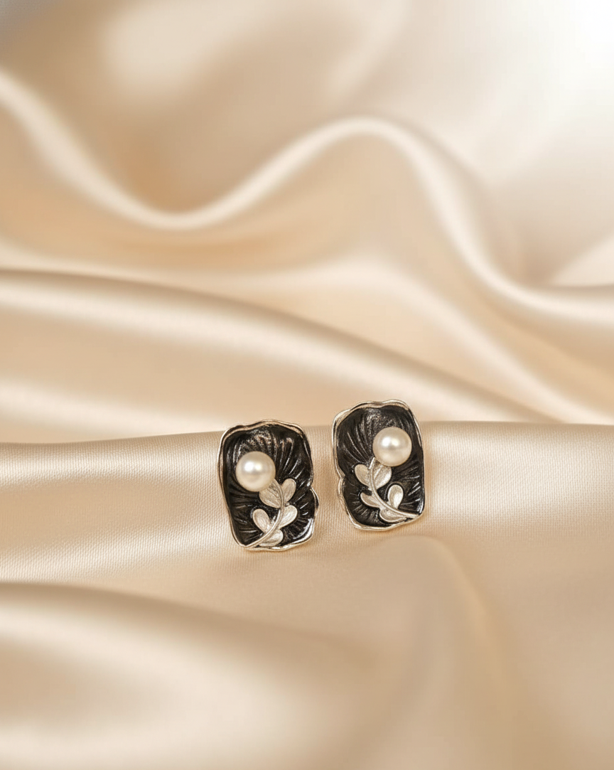 Pair of earrings with pearls on a beige satin background