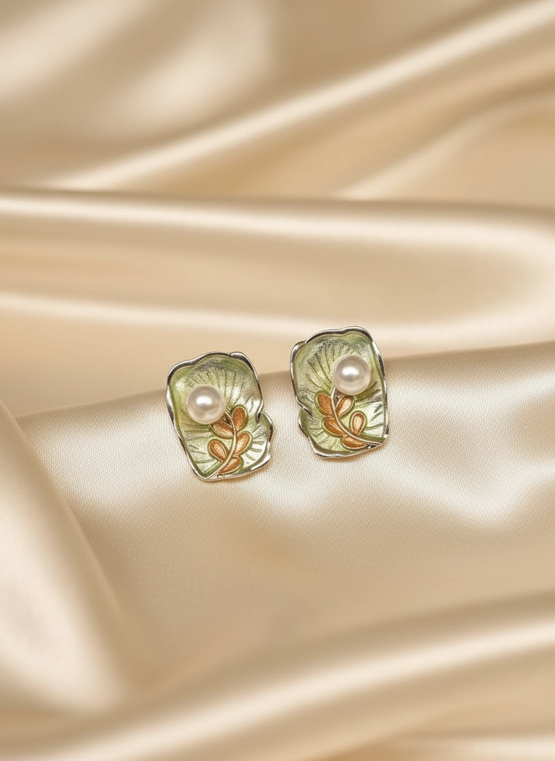Pair of earrings with pearl-like centers on a beige satin background