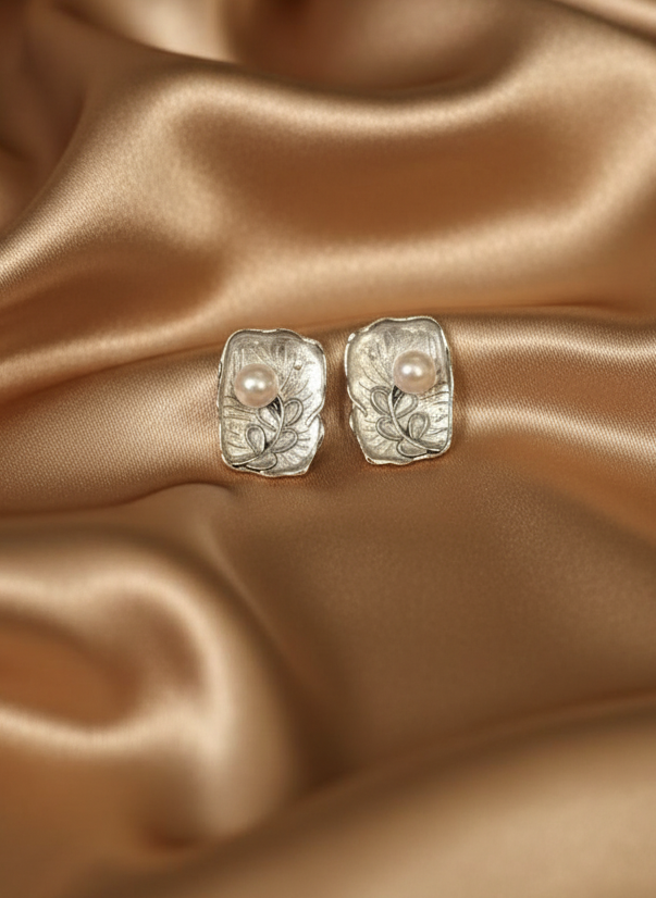 Silver earrings with pearls on a gold satin background