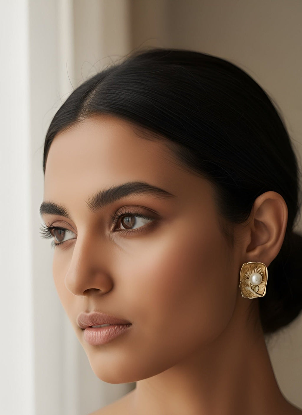 Woman wearing a gold earring with a neutral background