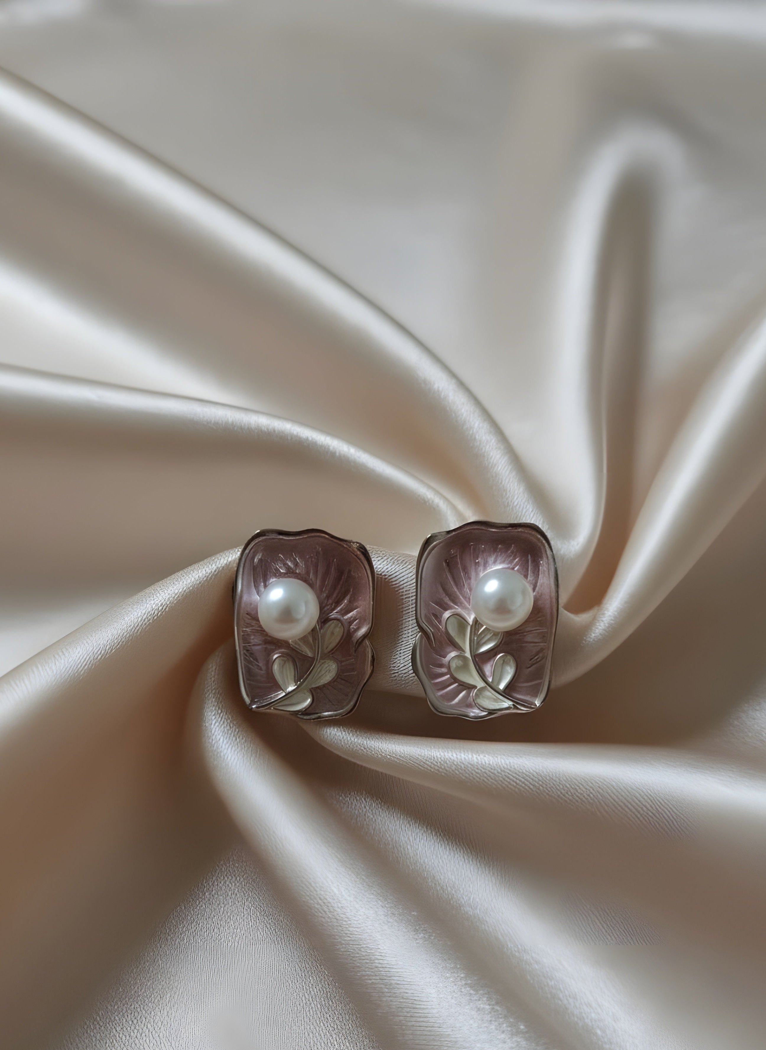 Pair of earrings with pearls on a satin surface