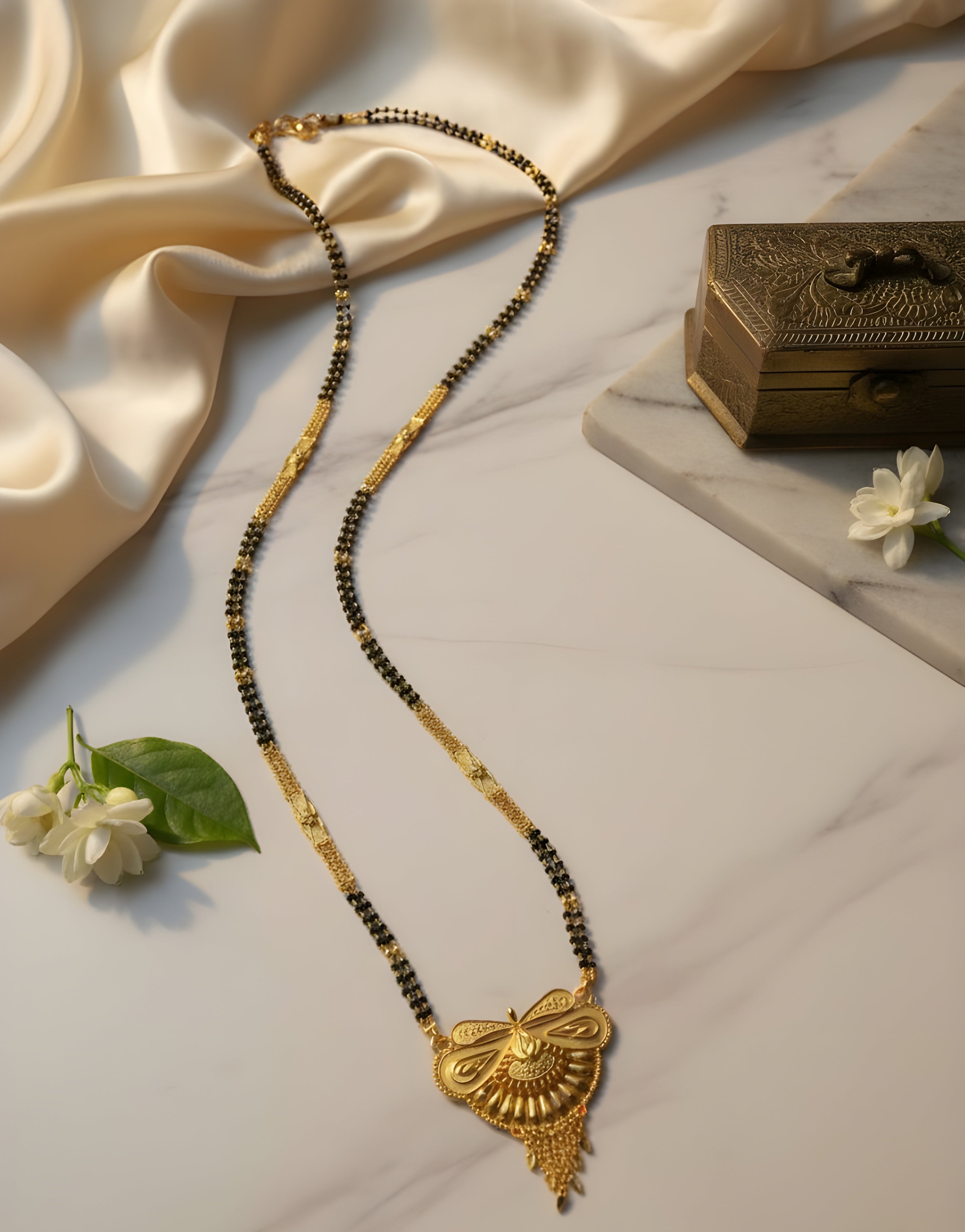Gold and black beaded necklace with decorative pendant on a light fabric background