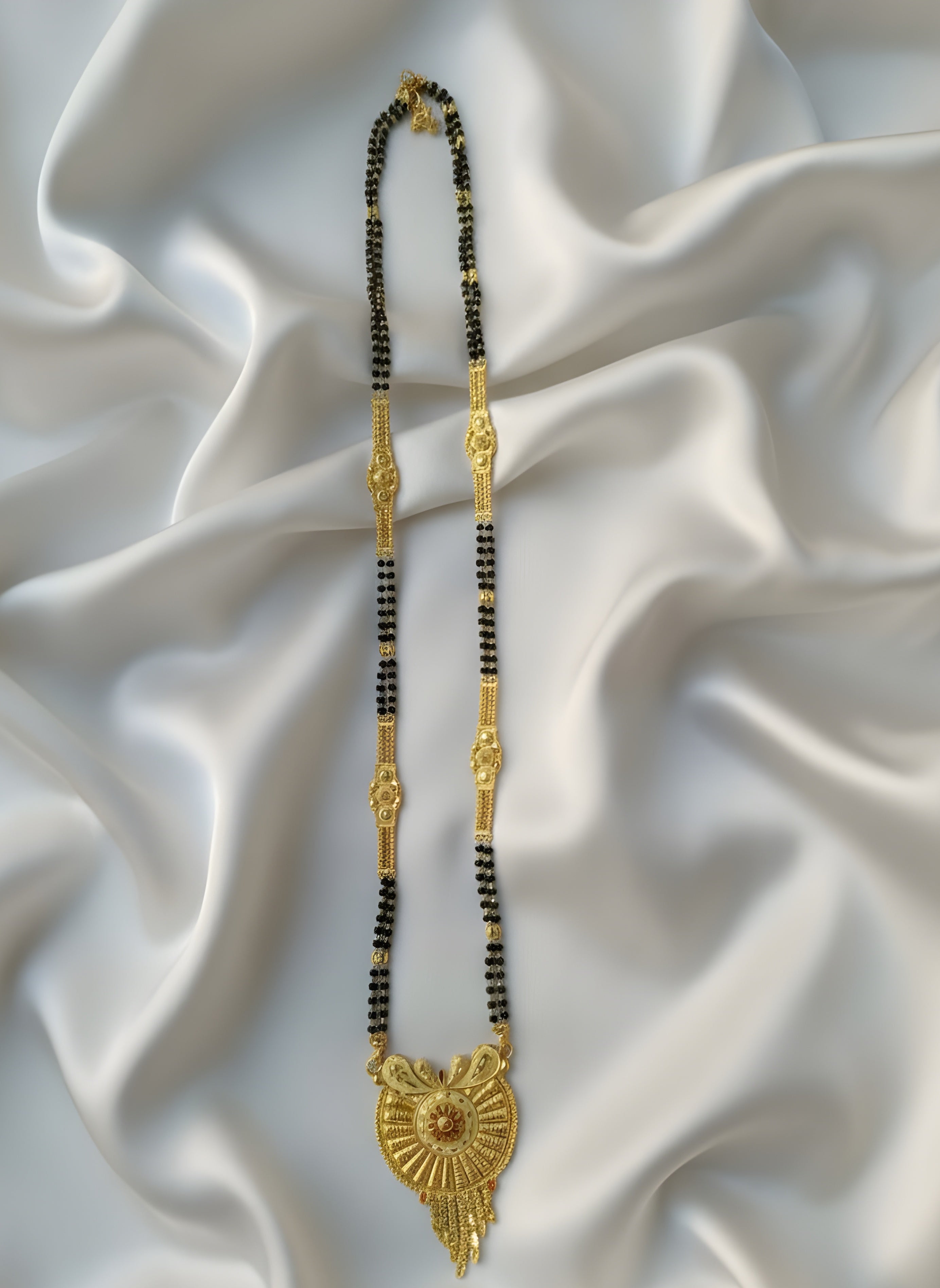 Gold and black beaded necklace on a textured white fabric background