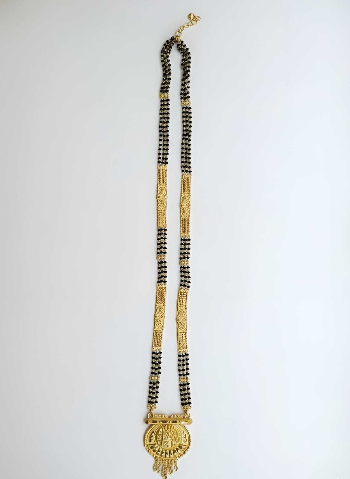 Long necklace with gold and black beads on a white background