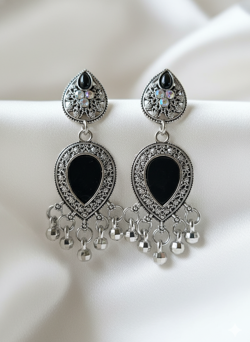 Pair of ornate earrings with black stones and dangling beads on a white background