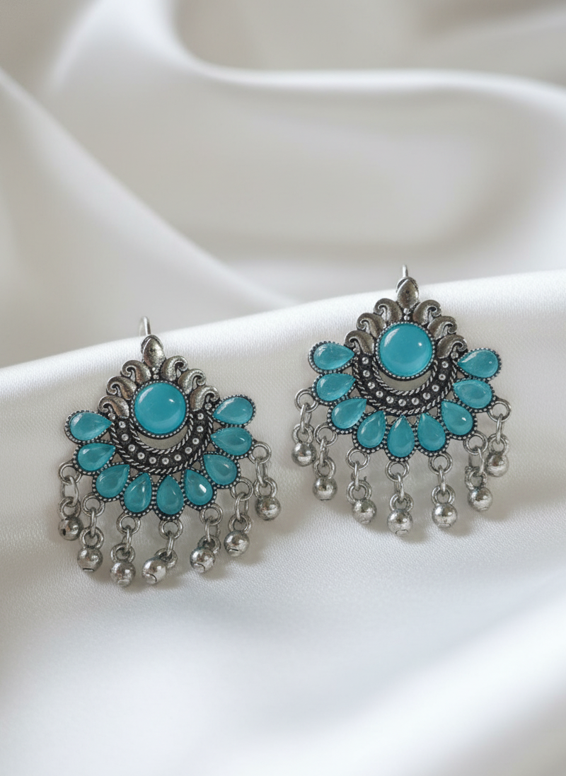 Turquoise and silver earrings on a white fabric background