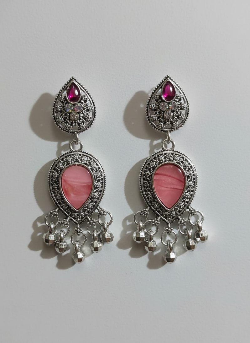 Pair of earrings with pink heart stones and silver accents on a light gray background
