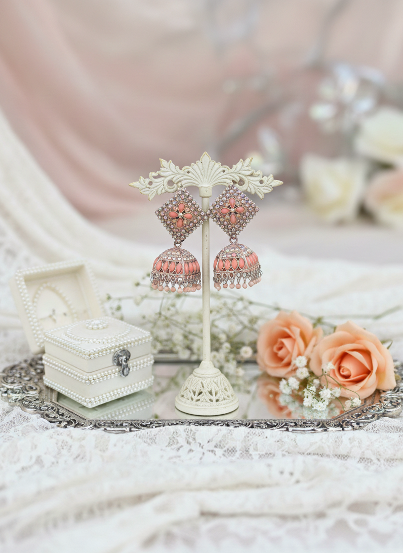 Jewelry set with earrings and a box on a decorative stand with flowers in the background