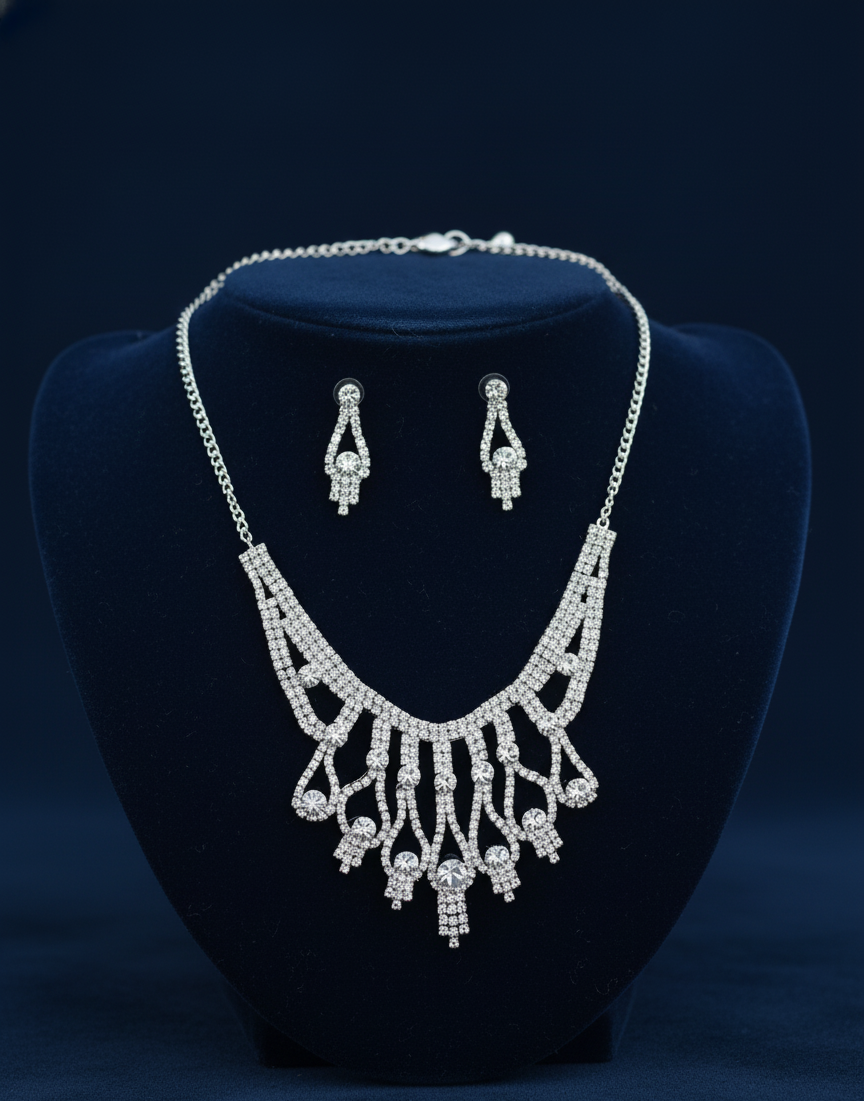 Silver necklace and earrings set on a dark blue stand with a dark blue background